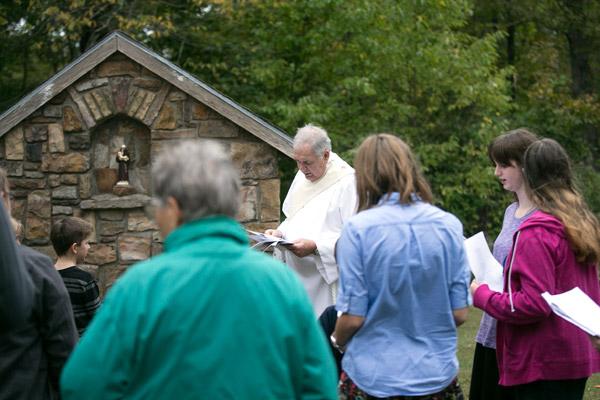 Pilgrims gather around Deacon Mike Henry to pray the fifth glorious mystery of the rosary at the statue of St. Anthony at Our Lady of the Ozarks Shrine. (Karen Schwartz photo)