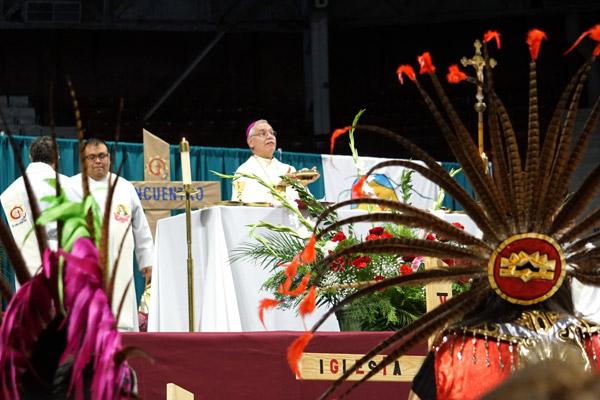 Aztec dancers stand while Bishop Taylor consecrates the bread and wine during Mass. (Malea Hargett photo)