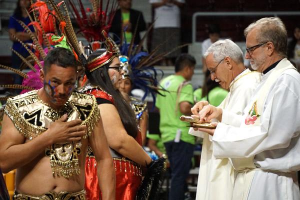 Aztec dancers receive Communion from Msgr. Scott Friend and Bishop Taylor during the Diocesan Encuentro Mass Nov. 18 at Barton Coliseum in Little Rock. (Malea Hargett photo)