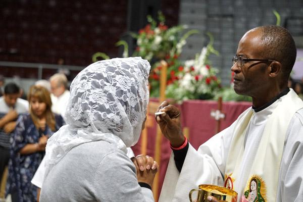 Father Eliseo Noel Njopmo of Fayetteville distributes Communion. (Malea Hargett photo)