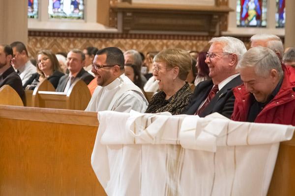 Father Rubio and the congregation laugh during a lighthearted-moment of Bishop Taylor’s homily. (Bob Ocken photo)