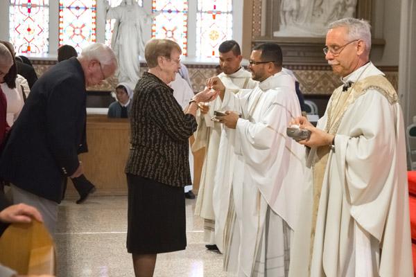 Father Rubio gives communion to Sue Wood of St. John Church in Hot Springs. Dennis and Sue Wood, parents of Father Mark Wood, sat with Father Rubio during the Dec. 16 ordination. (Bob Ocken photo)