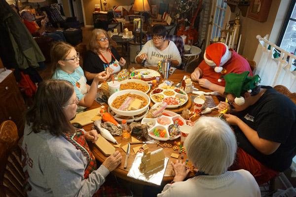 Jean Leffler (left, gray long sleeve shirt), friends and family work hard on Christmas cookie houses Dec. 21. (Aprille Hanson photo)