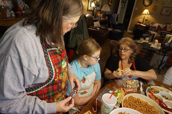 Jean Leffler (left) and Retha Fausett give some tips to CJ Fausett to make her cookie house even better. (Aprille Hanson photo)