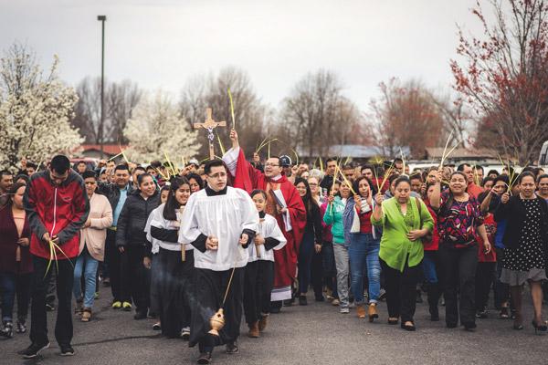 Associate pastor Father Ramses Mendieta and parishioners at St. Raphael Church in Springdale, holding palm branches, process around the church before Mass on Palm Sunday March 25 and reenact Jesus entering Jerusalem. (Travis McAfee photo)