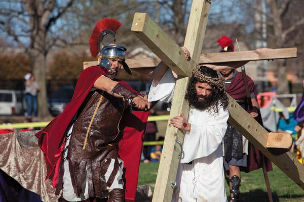 A guard, portrayed by Rigoberto Hernandez, whips Jesus, portrayed by Jesus Martinez, as he carries his cross during the Live Stations of the Cross on Good Friday at St. Vincent de Paul Church in Rogers. Hispanic parishioners organized the annual event with realistic costumes and props. (Paul Dufford photo)