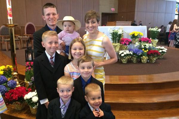 Jason and Erin Pohlmeier hoist Faustina, 1, as they gather their children in Easter finery for a photo at St. Joseph Church. They are (middle row left to right) Isaac, 11; Clare, 10 and Dominic 7. Front row left to right are Vincent, 5 and Damien, 3.