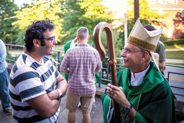 Egyptian student Wassim Khalil, 22 (left), stops by after Mass at St. Thomas Aquinas University Parish in Fayetteville to chat with Bishop Anthony B. Taylor Sept. 18, 2016. The conversation began in English and finished in French, a second language the two share. (Travis McAfee / Arkansas Catholic file)