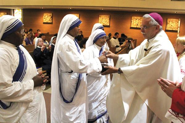 Sister Maria Jyoti hands Bishop Anthony B. Taylor the decanter of wine flanked by her fellow Missionaries of Charity Sisters during Mass for St. Teresa of Kolkata Sept. 4, 2016, at Our Lady of Good Counsel Church in Little Rocks. (Dwain Hebda / Arkansas Catholic file)