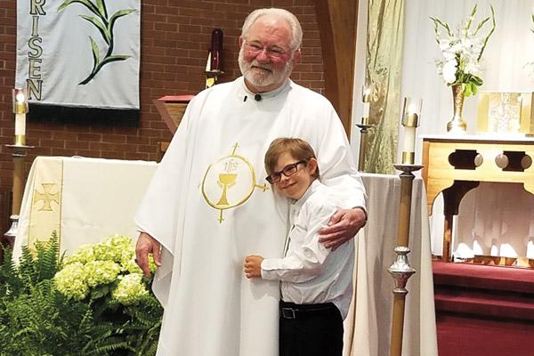 David Ray, 12, who has Down syndrome, hugs Father Jack Sidler after his first Communion in May 2017 at St. John Church in Russellville. (Photo courtesy Ray family)
