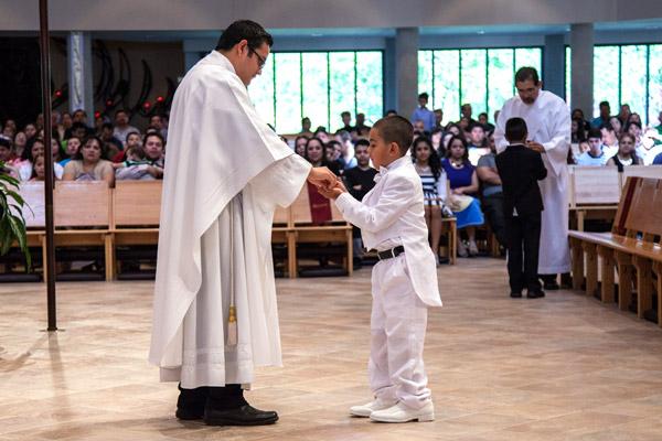 Angelo Figueroa, then 8 years old, receives first Communion from Father Juan Manjarrez at St. Vincent de Paul Church in Rogers in 2014. Right after receiving Communion, Figueroa, who was born with a brain disorder called agenesis of the corpus callosum, joyfully said “I got it,” Debbie Dufford said, who helps prepare those with special needs for the sacraments. (Paul Dufford photo)
