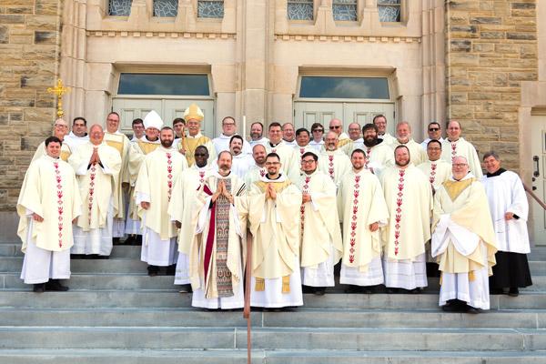 Newly ordained Fathers Reginald Udouj (front left) and Cassian Elkins pose with Bishop Anthony B. Taylor, Abbot Leonard Wangler and fellow priests following their ordination July 14. (Bob Ocken photo)