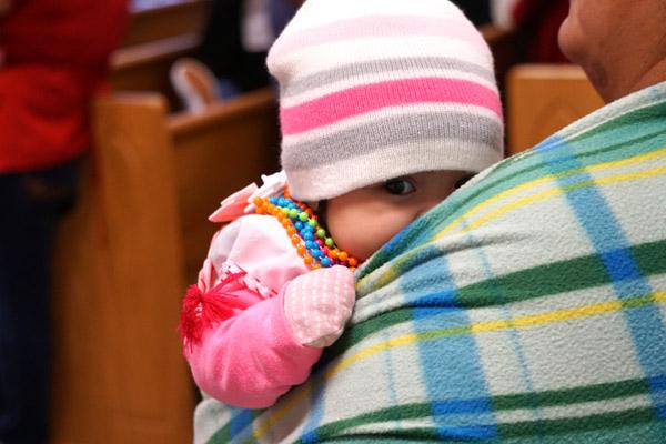 A baby sneaks a peek over her mother's shoulder during the Our Lady of Guadalupe Mass Dec. 8. (Malea Hargett photo)