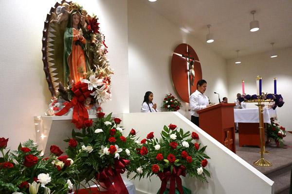 Red and white roses and carnations surround the statue of Our Lady of Guadalupe during Mass Dec. 8 at Holy Spirit Church in Hamburg. (Malea Hargett photo)