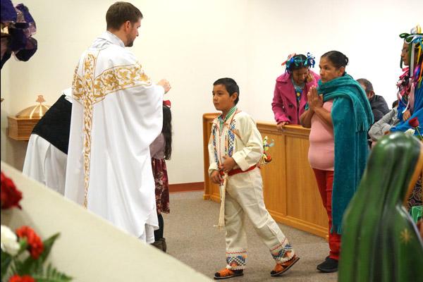 A young parishioner dressed in traditional Mexican clothing approaches pastor Father Stephen Hart for Communion. (Malea Hargett photo)