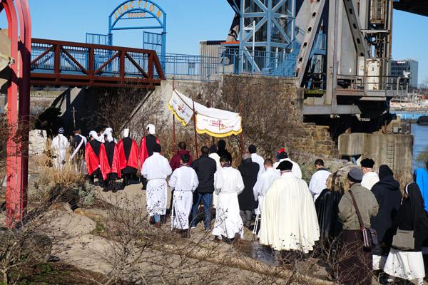 A seminarian carrying a cross and the Fourth Degree Knights of Columbus lead the procession near the Arkansas River.  (Malea Hargett photo)
