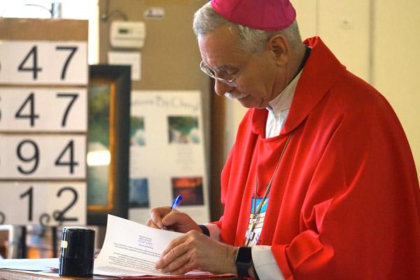Bishop Taylor signs letters to Pastor Father Tony Robbins, of St. Joseph Church in Conway, to make the Masses in Greenbrier the St. Oscar Romero Catholic Community on March 16. (Aprille Hanson photo)