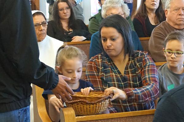 The faithful donate toward their new community during the offering. In order to one day be established as a parish, the community will have to be able to support itself financially. (Aprille Hanson photo)