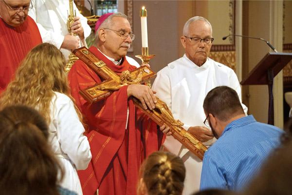 Bishop Anthony B. Taylor holds a wooden crucifix for parishioners to kiss during the Good Friday service at the Cathedral of St. Andrew in Little Rock. (Malea Hargett photo)