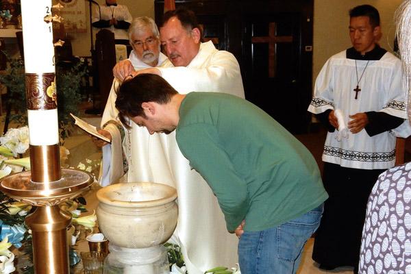 Father George Sanders, pastor of St. Mary of the Springs Church in Hot Springs, baptizes Ryan Burton during the Easter Vigil Mass on Holy Saturday, April 20. (Jim Keary photo)
