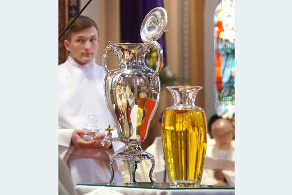 The oil of catechumens, used in the baptism of infants, is placed in front of Bishop Taylor at the Chrism Mass by seminarian Joseph Jones (left), waiting for a blessing. (Aprille Hanson photo)