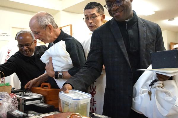 After the Chrism Mass at the Cathedral of St. Andrew, priests flood into McDonald Hall to pick up their filled containers of oil for the year. Priests pictured are Father Aby Abraham, IMS (left), Father Bill Elser, Father Toshio Sato, CM, and Father Joseph Archibong. (Aprille Hanson photo)