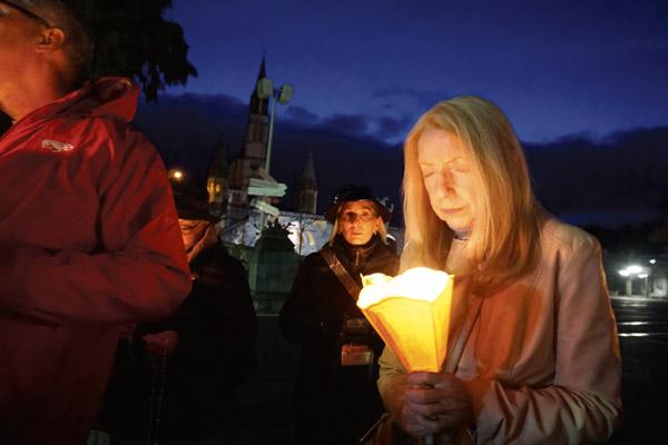 Ava LaChance, a member of St. Stephen Church in Bentonville, prepares for a rosary candlelight procession to the shrine at Lourdes with the Arkansas group April 3. (Malea Hargett photo)