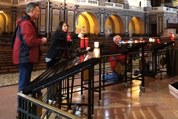 Terry and Anna Canterbury, members of Holy Redeemer Church in El Dorado, light a votive candle in the Basilica of St. Therese in Lisieux April 9. (Malea Hargett photo)