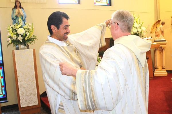 With the assistance of Brother Luke Turner, OSB, of St. Benedict Abbey in Kansas, Daniel Velasco slips on the vestments of a deacon during his May 17 ordination Mass. (Dwain Hebda photo)
