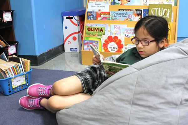 Sophia Varela gets lost in a good book during afternoon reading time in Elizabeth Krupsaw's first-grade classroom at St. Edward School in Little Rock. (Dwain Hebda photo)