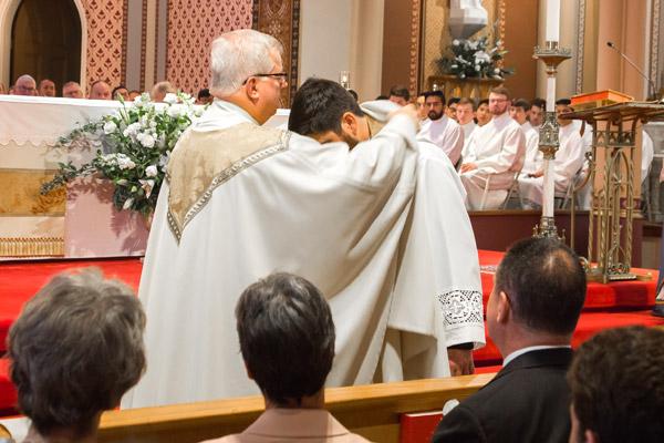 His pastor Msgr. Francis Malone assists Father Jon Miskin in putting on the vestments of a priest, including a stole and chasuble. (Bob Ocken photo)
