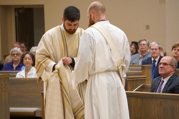 Deacon Jon Miskin, who was ordained a priest three days later, helps vest Joseph Friend with the stole and dalmatic worn by a deacon. (Malea Hargett photo) 