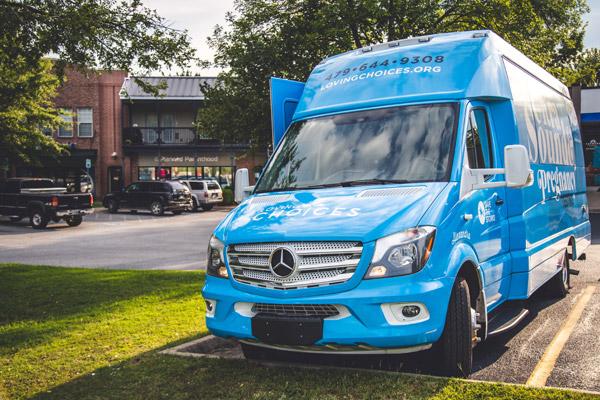 The Loving Choices ultrasound bus, nicknamed Alexandra, shares the parking lot with Planned Parenthood on the clinic's last day of business. Alexan-dra is named after a child whose life was saved from abortion. (Travis McAfee photo)