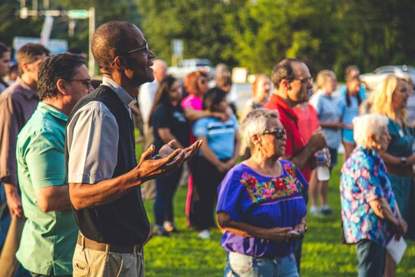 Father Eliseo Noel Njopmo, associate pastor at St. Joseph Church in Fayetteville, prays with more than 100 other people during a prayer vigil outside the now-closed Planned Parenthood clinic in Fayetteville July 25. (Travis McAfee photo)