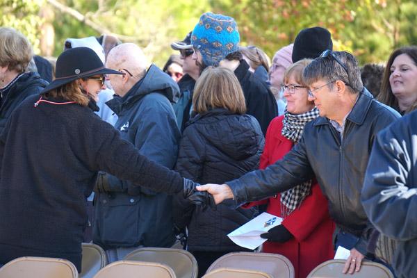 Attendees extend the sign of peace during the All Souls Day Mass at Calvary Cemetery. (Malea Hargett photo)