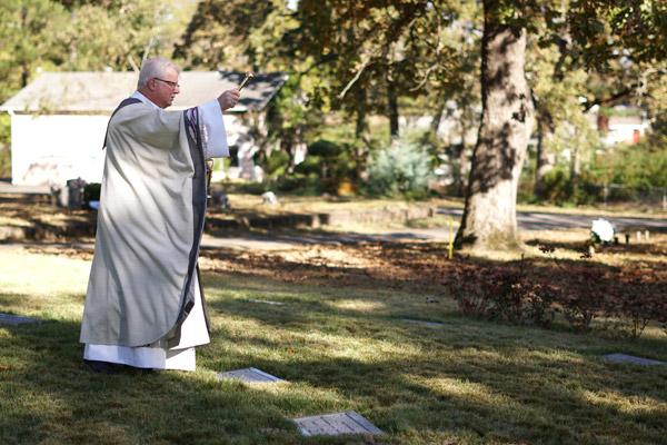 Msgr. Francis I. Malone blesses the graves of diocesan priests buried in Priests’ Circle. (Malea Hargett photo)