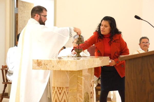 After the bishop anoints the altar with sacred chrism, a parishioner wipes the altar and dresses it with altar linens. (Malea Hargett photo)