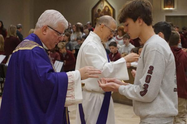 Bishop-elect Malone gives Communion to eighth-grade student Joseph Castillo along with Deacon Danny Hartnedy on Dec. 20 at Christ the King Church. (Aprille Hanson photo) 
