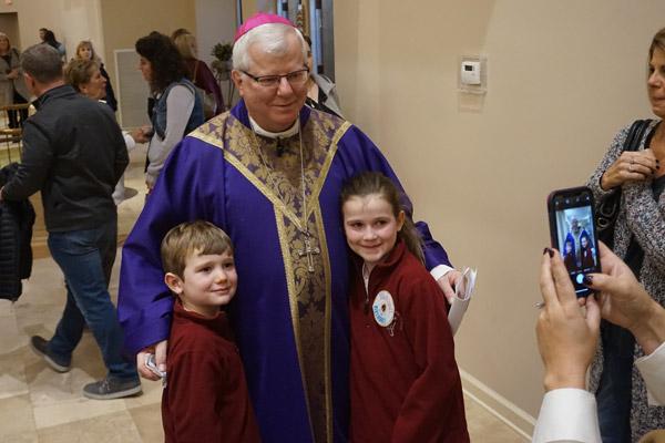 Parents and students lined up to hug and take photos with Bishop-elect Malone, including kindergartner Henry McNulty and third-grader Maggie McNulty. (Aprille Hanson photo) 
