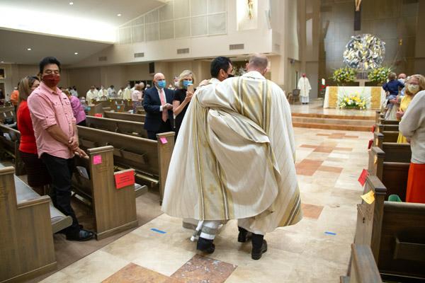 Father Daniel Velasco (left) and Father Joseph Friend embrace, returning to the altar for photos following their priestly ordination Mass Aug. 15. (Bob Ocken photo)