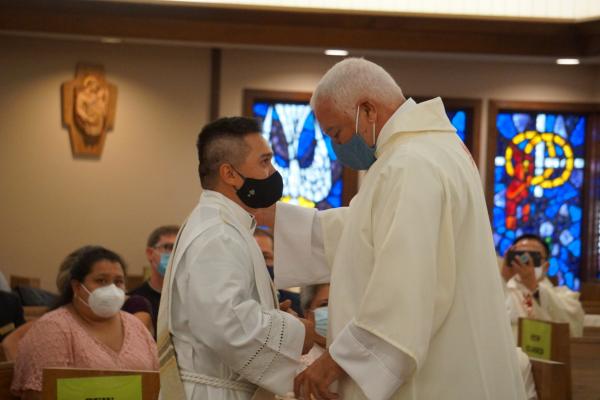 Deacon Mike Alberson (right) helps Deacon Alex Smith vest in the liturgical vestments of a deacon. (Malea Hargett photo)