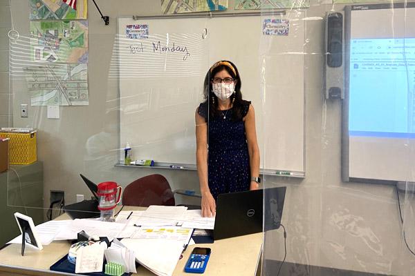 Catholic High School teacher Shannon Fratesi teaches a chemistry class behind plexiglass and a clear shower curtain. She has taken extra precautions due to having Multiple Sclerosis. (Father Patrick Friend photo) 