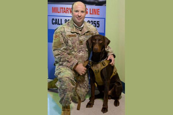Father Matt Garrison smiles with Cletus, a certified therapy dog, at the Air National Guard base in Fort Smith in September to promote wellness and suicide prevention. Cletus has helped countless veterans struggling with PTSD. (Courtesy Father Matt Garrison)
