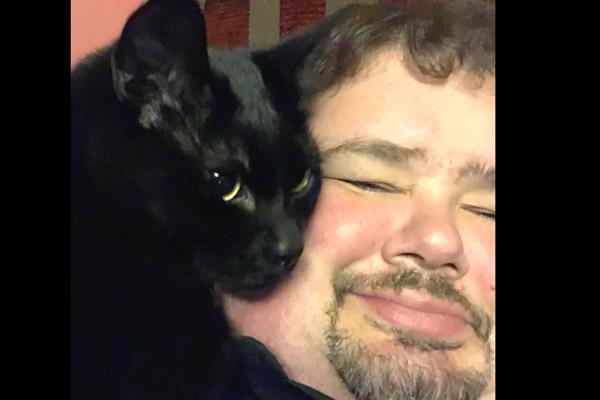 Father Shaun Wesley snuggles with his cat Jude Jan. 12. He adopted Jude and Maxine, both black cats, for companionship and so fur wouldn’t show on his clerics. (Courtesy Father Shaun Wesley)