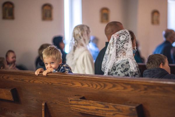 A toddler smiles before the first Mass at Our Lady of Sorrows Parish in Springdale. (Travis McAfee photo)