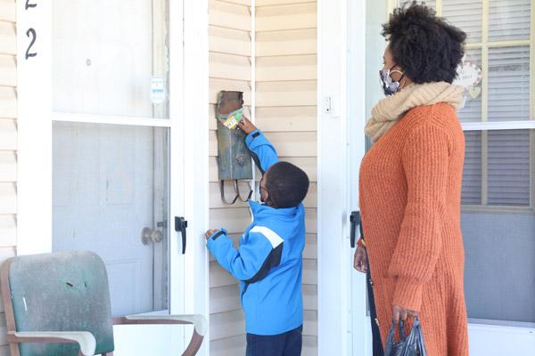 Dominic Mitchell, 3, leaves candy in a neighbor’s mailbox, assisted by his mother, Dionne Mitchell, during the march in honor of Dr. Martin Luther King Jr., hosted Jan 17 by St. Augustine Church in North Little Rock. (Dwain Hebda photo) 