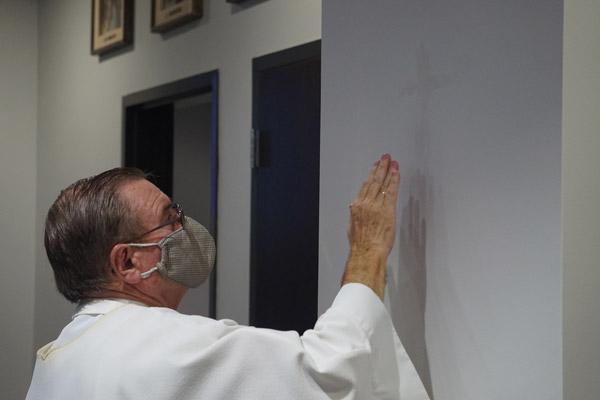 Pastor Father Ernie Hardesty anoints the wall with oil, part of the Rite of Dedication of a Church and an Altar at the new parish April 14. Four corners of the church were anointed to signify the four Gospels. (Aprille Hanson Spivey photo) 