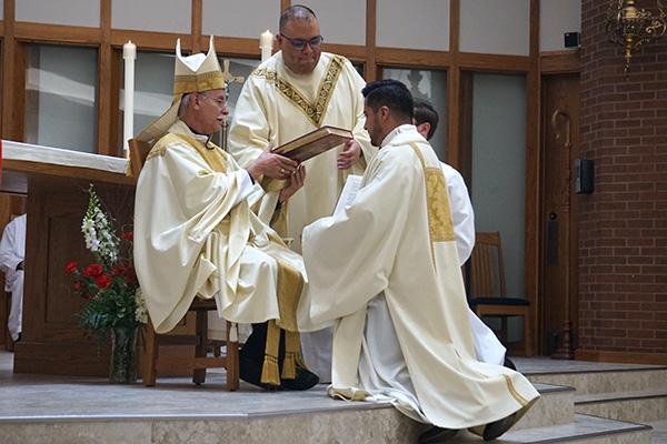 As part of the diaconate ordination rite, Bishop Anthony B. Taylor hands the newly ordained Deacon Jaime Nieto the book of the Gospels, saying, “Receive the Gospel of Christ, whose herald you have become. Believe what you read, teach what you believe and practice what you teach.” (Aprille Hanson Spivey photo) 