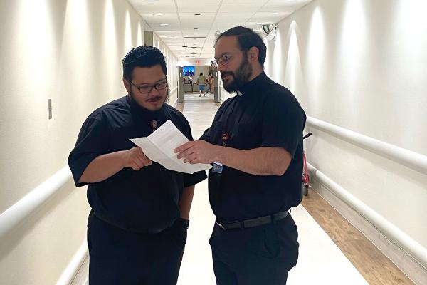 During their shift at Baptist Health Medical Center in Little Rock, seminarian Luis De La Cruz (right) of the Archdiocese of San Antonio, reviews his schedule July 13 with seminarian Santiago Perez of the Diocese of San Bernardino, Calif. (Courtesy Baptist Health)