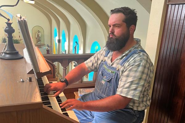 Seth Smithee, the new organist at St. John the Baptist Church in Engelberg, plays the organ before Mass. Courtesy Jane Smith.
